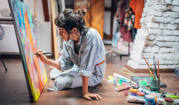 Artiste en train de peindre sur une toile dans un atelier, illustrant le processus de création artistique
