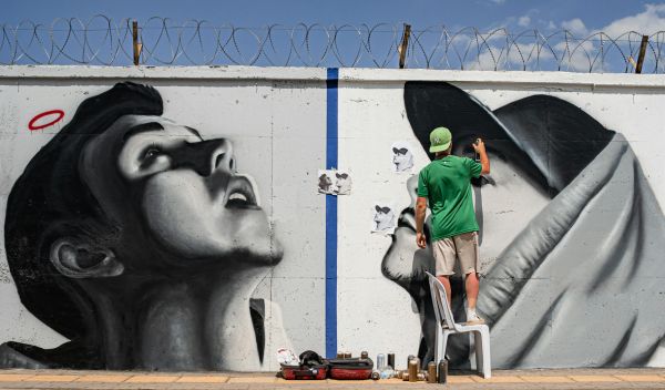 Artiste réalisant une fresque murale en extérieur, illustrant la visibilité et l’exposition de son travail